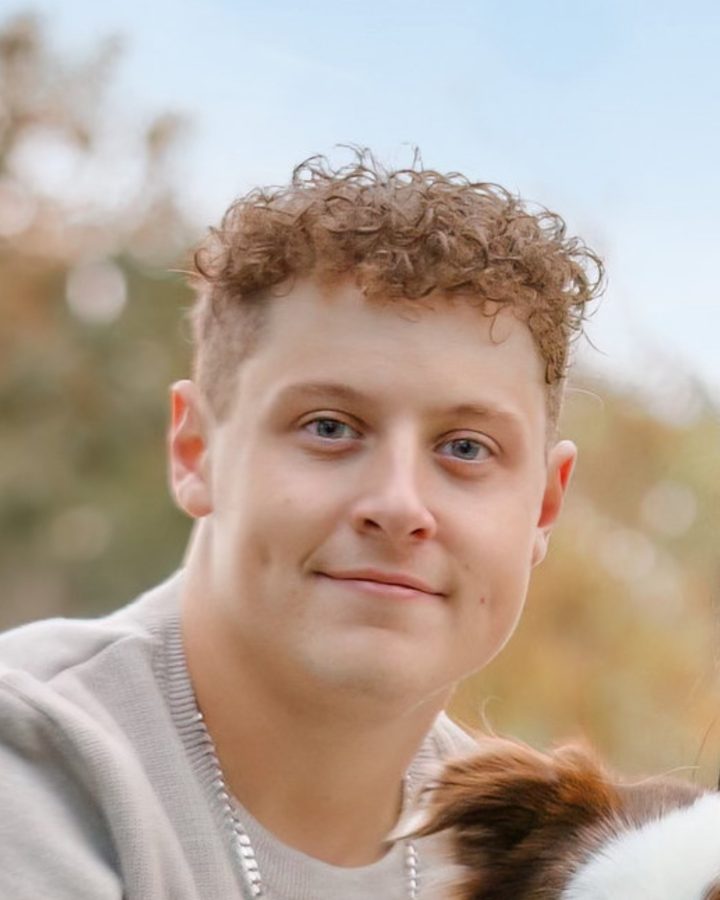 Coleton Boutilier smiling outdoors, with his dog beside him